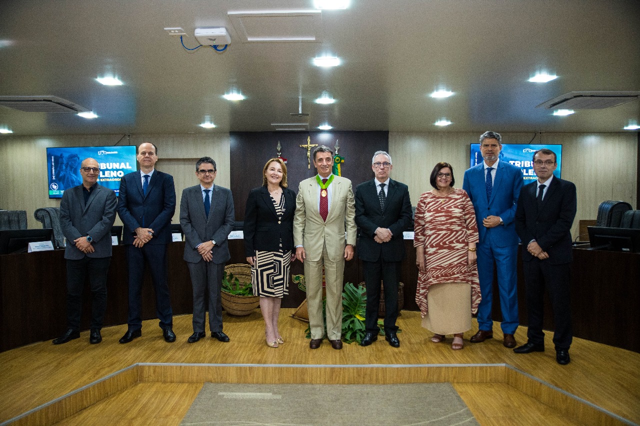 Foto colorida do Alessandro Cortese no meio pousando para fotografia ao lado Desembargador Almiro Padilha, Desembargadora Elaine Bianchi, Desembargador Cristóvão Suter, Desembargador Ricardo Oliveira, Desembargador Erick Linhares e Desembargador Fernando Mallet, e Procuradora Cleonise Andritta. Todos estão em pé pousando para fotografia no centro do Tribunal Pleno.