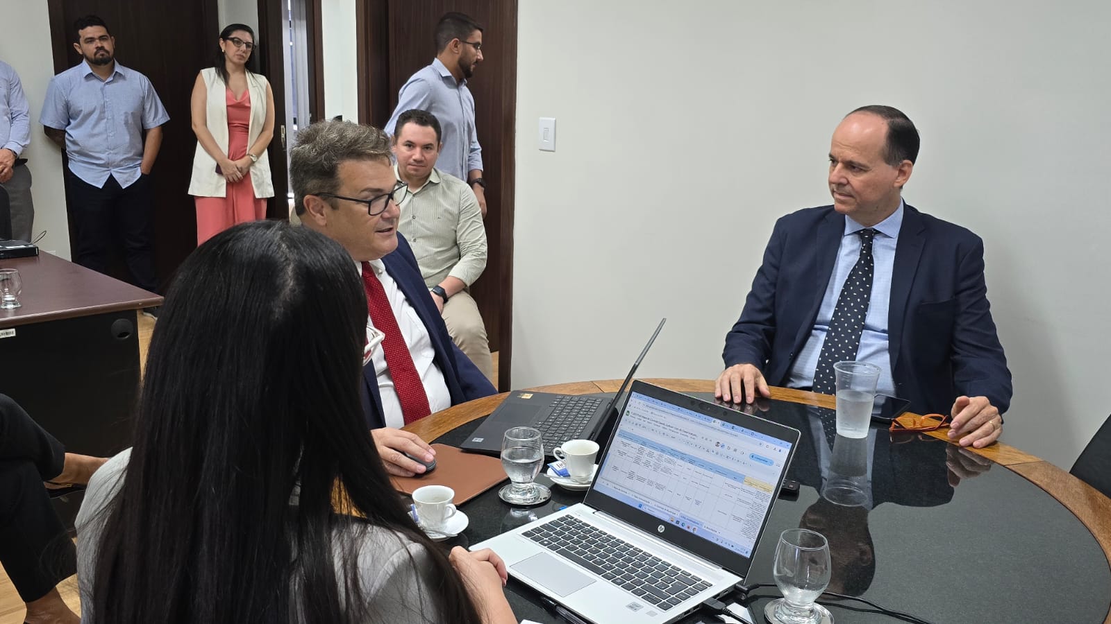 Imagem colorida contém sete pessoas em voltas de uma mesa de reunião, sendo uma delas o Coordenador do Centro e Memória e Cultura do Poder Judiciário de Roraima, desembargador Cristóvão Suter.