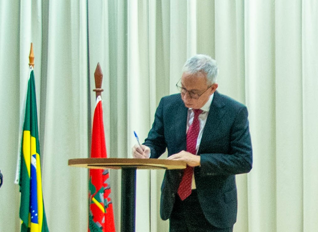 Foto colorida mostrando o Desembargador Almiro Padilha assinando um documento